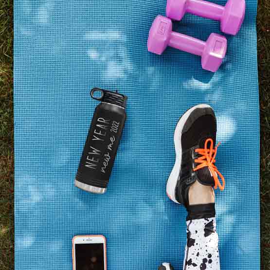Black 32 Ounce Water Bottle With Straw And Engraved With New Year New Me Text And Year On Yoga Mat Near Weights And Phone