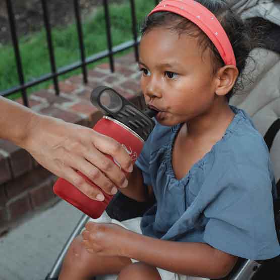 Hand Serving Red Stainless Steel Child Water Bottle With Straw And Engraved Name To Little Girl In Stroller Outdoors