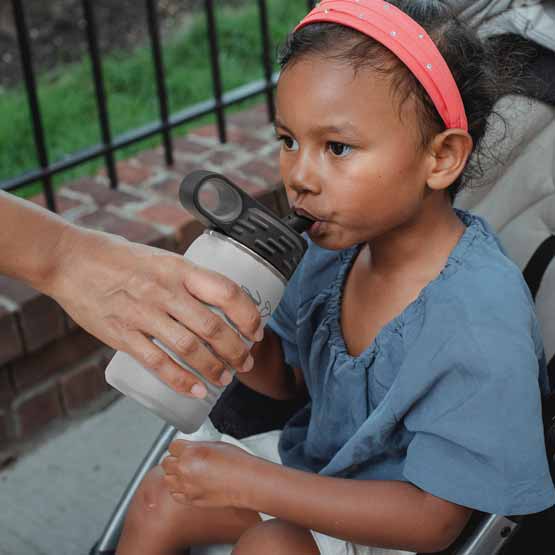 Hand Serving White Stainless Steel Child Water Bottle With Straw And Engraved Name To Little Girl In Stroller Outdoors
