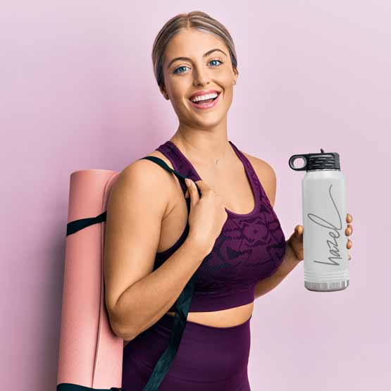 Woman In Workout Clothes Carrying Yoga Mat And White Thirty Two Ounce Water Bottle With Straw And Engraved Name