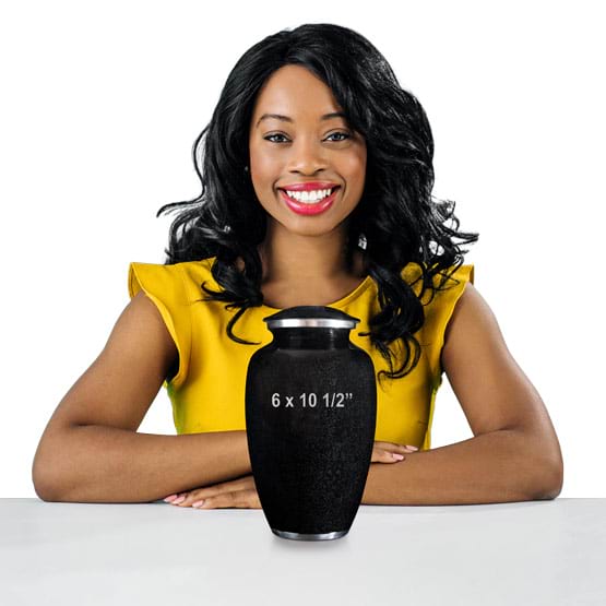 Woman Sitting At White Table Behind A Custom Black Aluminum Cremation Urn Showing Measurements Against A White Background