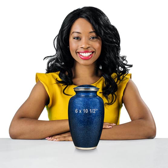 Woman Sitting At White Table Behind A Custom Blue Aluminum Cremation Urn Showing Measurements Against A White Background