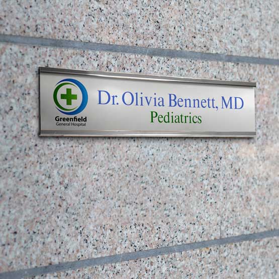 Silver Aluminum Office Plate Printed With Hospital Logo And Doctor Details Mounted On Concrete Wall Via Silver Bracket