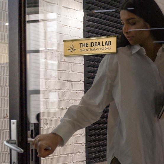 Woman Closing Office Door With Brass Office Plate Laser Fused With Lab Logo And Details Mounted Via Gold Bracket