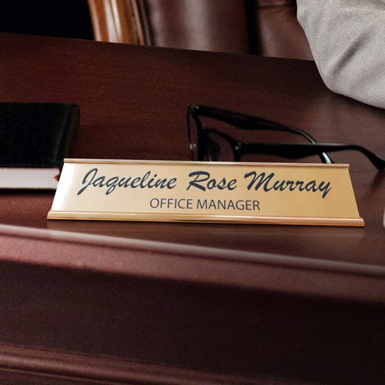 Custom Bronze Desk Name Plate On Dark Wood Desk Near Glasses.