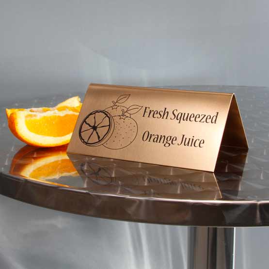 Custom Bronze Table Tent Name Plate On Metal Table Near Orange.