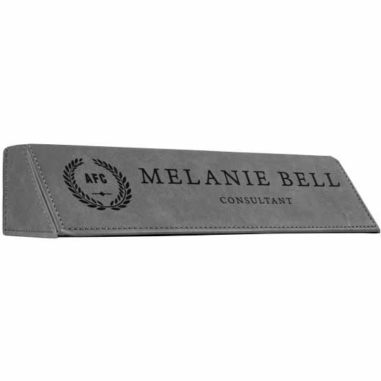 Gray Faux Leather Desk Wedge Laser Engraved With Sample Logo And Employee Name And Role Against White Background