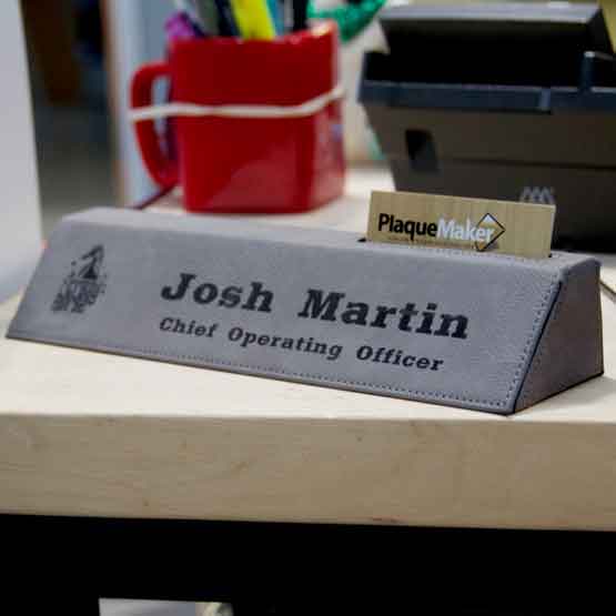 Gray Faux Leather Desk Wedge With Card Slot And Engraved With Logo And Chief Officer Details On Wood Desk With Phone