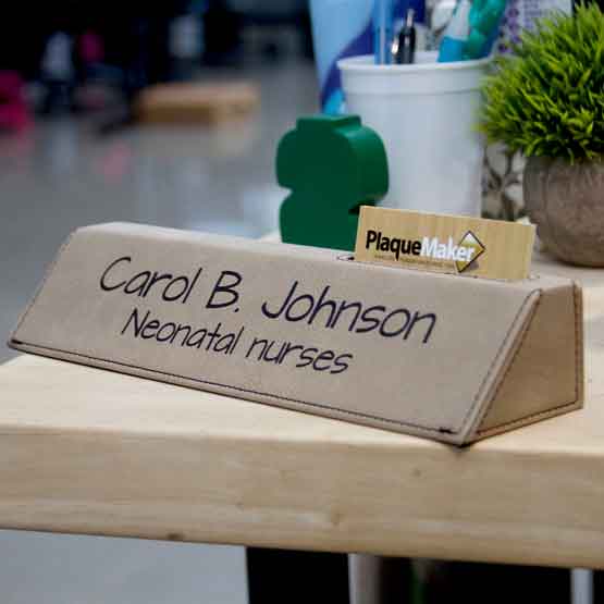 Light Brown Faux Leather Desk Wedge With Card Slot And Laser Engraved With Logo And Nurse Details On Office Desk With Plant