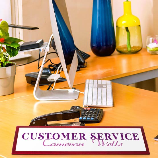 Office desk with computer, keyboard, calculator, and a custom 'Customer Service name plate.