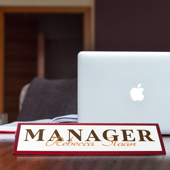 Laptop on a desk with a custom 'Manager' nameplate in front
