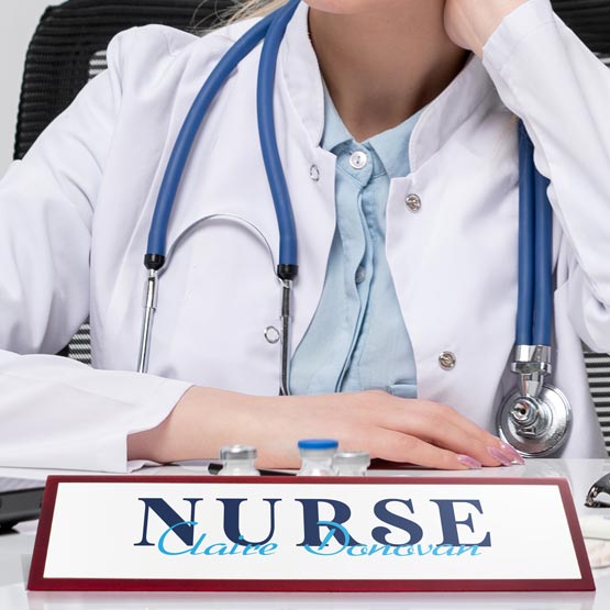 A nurse wearing a white coat with a stethoscope, sitting at a desk with a custom 'Nurse' nameplate.
