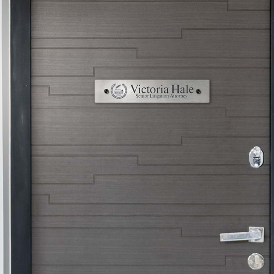 Stainless Steel Office Plate With Black Standoffs And Logo And Attorney Details Mounted Onto Interior Office Door