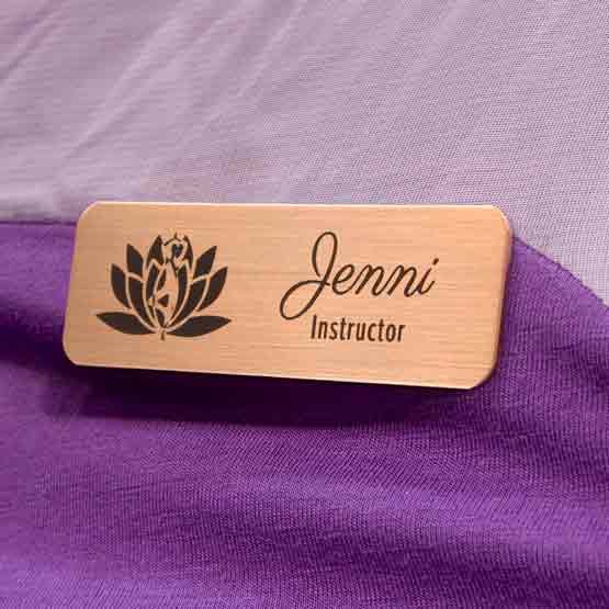 Custom Copper Magnetic Name Badge Laser Fused With Flower Art And Jenni Instructor Text Fastened To A Purple Sweater