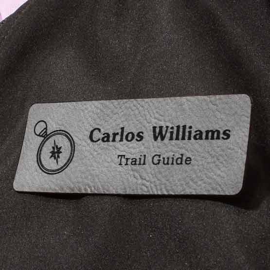 Gray Faux Leather Name Tag With Title And Logo On Black Jacket.