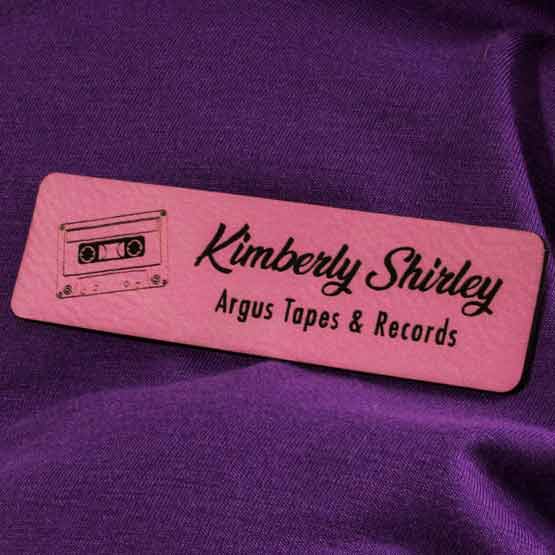 Faux Leather Pink Name Tag With Logo On Purple Shirt.