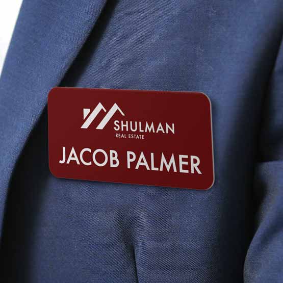 Plastic Red Magnetic Name Badge Laser Engraved With Real Estate Business Logo And Name Fastened To A Blue Business Suit