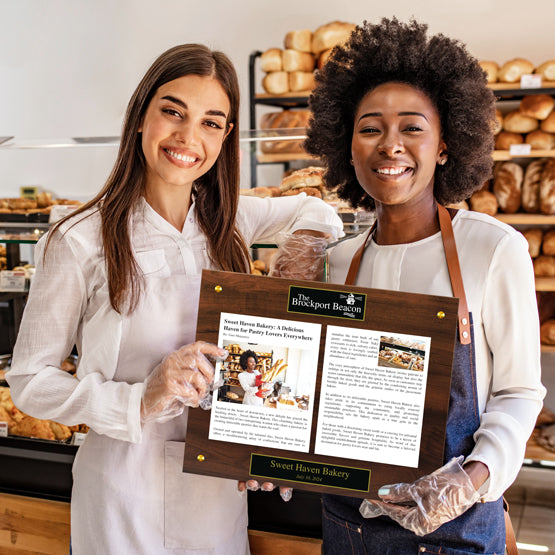Two Happy Women Holding An Acrylic Newspaper Plaque For Their Bakery Business
