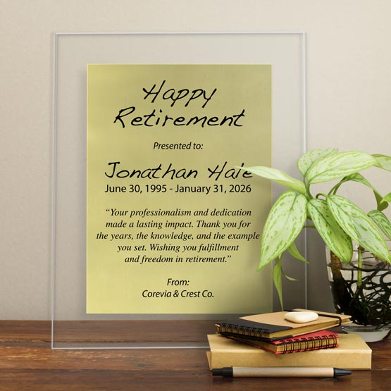 Gold Aluminum Plaque With Clear Acrylic Board And Printed With Happy Retirement Message On Shelf With Plant And Notebooks