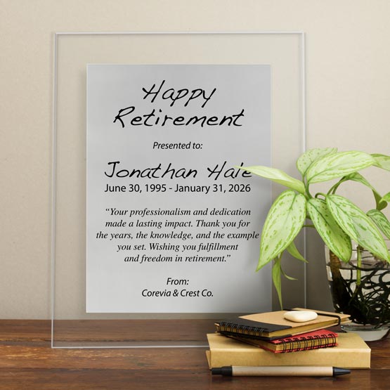 Silver Aluminum Plaque With Clear Acrylic Board And Printed With Happy Retirement Message On Shelf With Plant And Notebooks