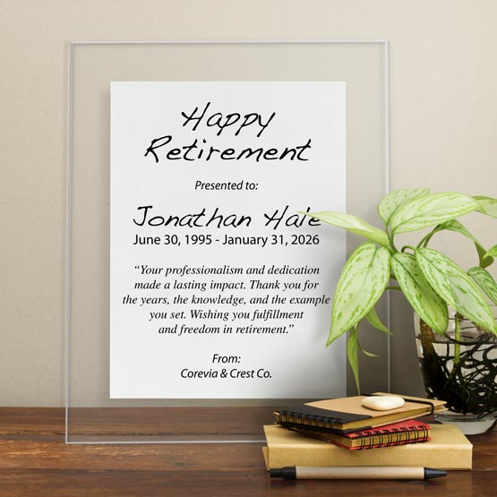 White Aluminum Plaque With Clear Acrylic Board And Printed With Happy Retirement Message On Shelf With Plant And Notebooks
