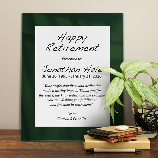 White Aluminum Plaque With Green Acrylic Board And Printed With Happy Retirement Message On Shelf With Plant And Notebooks