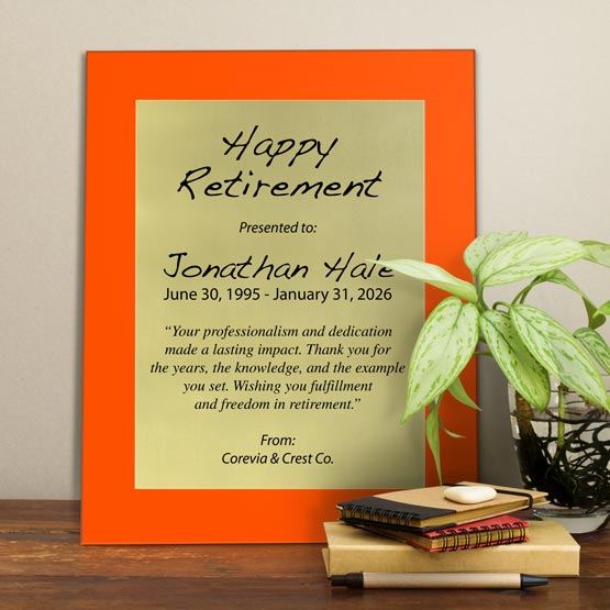 Gold Aluminum Plaque With Orange Acrylic Board And Printed With Happy Retirement Message On Shelf With Plant And Notebooks