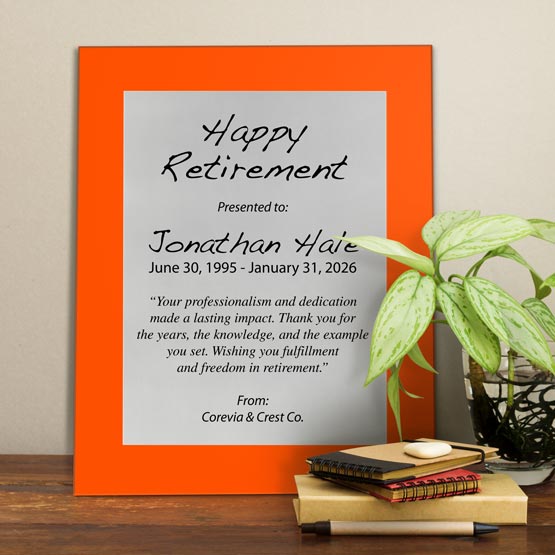 Silver Aluminum Plaque With Orange Acrylic Board And Printed With Happy Retirement Message On Shelf With Plant And Notebooks