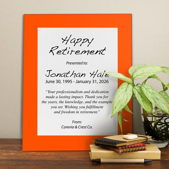 White Aluminum Plaque With Orange Acrylic Board And Printed With Happy Retirement Message On Shelf With Plant And Notebooks