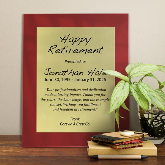 Gold Aluminum Plaque With Red Acrylic Board And Printed With Happy Retirement Message On Shelf With Plant And Notebooks