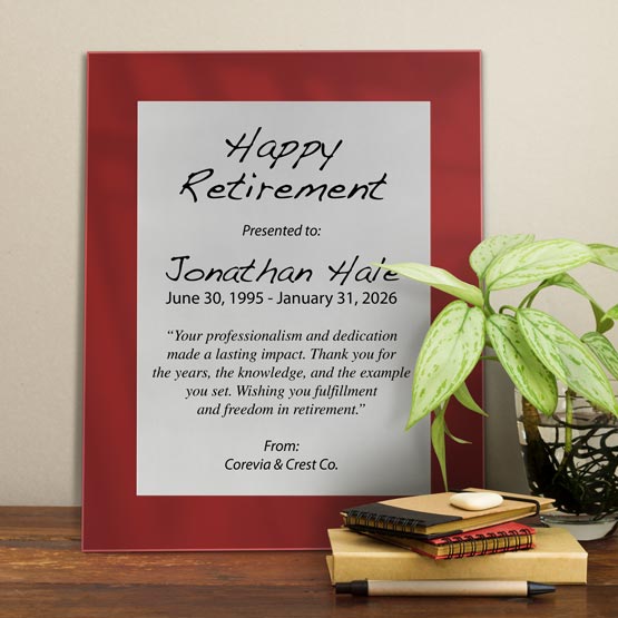 Silver Aluminum Plaque With Red Acrylic Board And Printed With Happy Retirement Message On Shelf With Plant And Notebooks