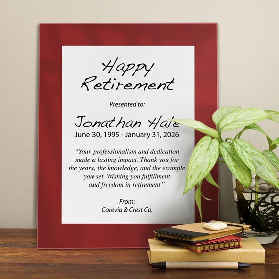 White Aluminum Plaque With Red Acrylic Board And Printed With Happy Retirement Message On Shelf With Plant And Notebooks