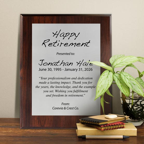 Silver Aluminum Plaque With Cherry Board And Printed With Happy Retirement Message On Shelf With Plant And Notebooks