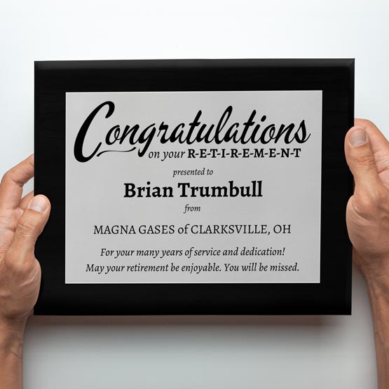 Man Hands Holding Custom Retirement Plaque With Silver Aluminum Plate On Marble Board Featuring Congratulations Message