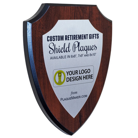 A silver metal in the shape of shield on a wooden board with printed text and placeholder art, set at a slight angle on a white background.