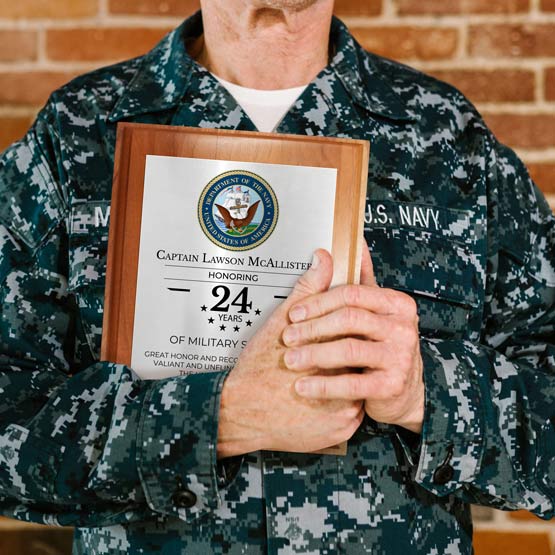A US Navy soldier holding a custom printed aluminum plaque in full color honoring 24 years of military service. 