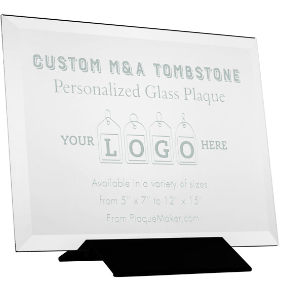 A clear personalized glass tombstone plaque displayed on a black stand against a white background with engraved text and a placeholder artwork.