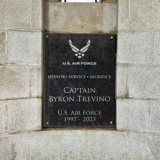 Custom granite plaque with the US Airforce Logo and memorial for Captain Byron Trevino attached to a gray stone wall.