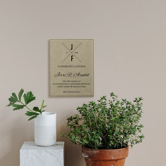 Light Brown Faux Leather Plaque With Logo And Years Of Service Congratulations Message On A Living Room Wall Above Plants