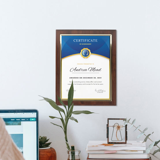Certificate Plaque With Wood Board And Gold Frame And Achievement Certificate On Office Wall Above Desk With Laptop And Books