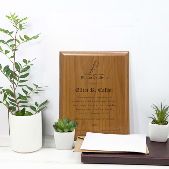 Solid Red Alder Wood Plaque Engraved With Award Message And Logo On A White Office Desk With Potted Plants And Notebook
