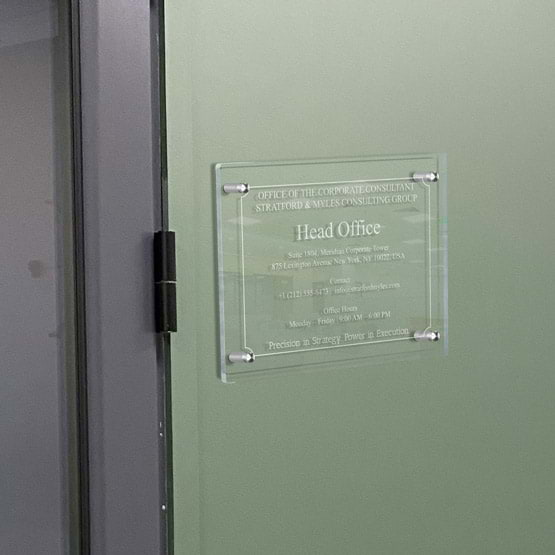 Clear Acrylic Sign With Frosted Engravings Of Head Office Details Mounted Onto Office Wall Via 4 Silver Standoffs Beside Door