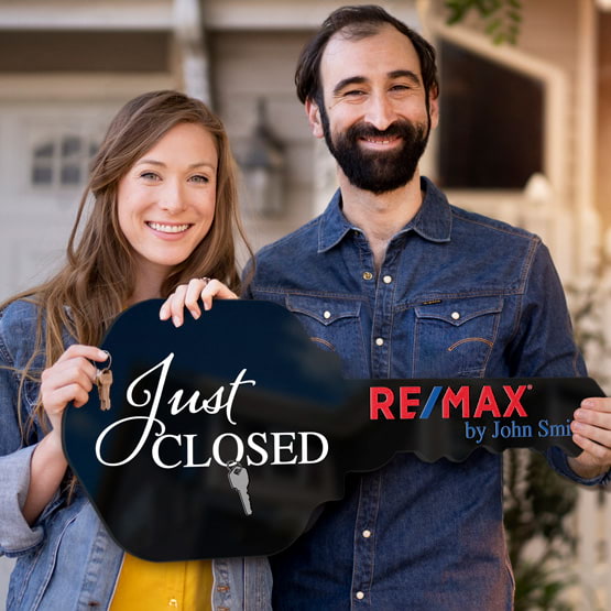 Happy Couple Outside Home Holding A House Key Shaped Black Acrylic Sign Printed With Just Closed Message And Logo And Name
