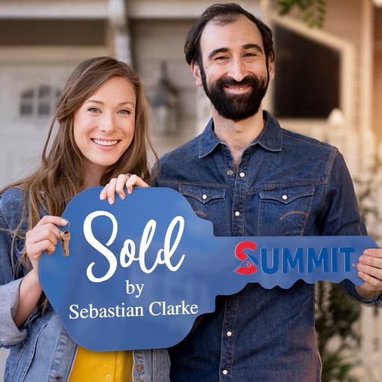 Happy Couple Outside Home Holding A House Key Shaped Blue Acrylic Sign Printed With Sold By Message And Logo And Name