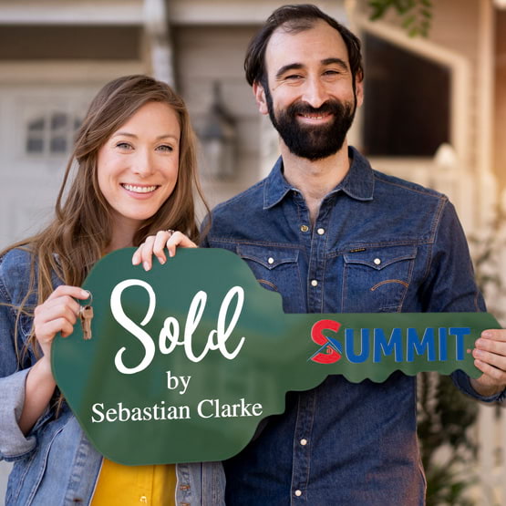 Happy Couple Outside Home Holding A House Key Shaped Green Acrylic Sign Printed With Sold By Message And Logo And Name