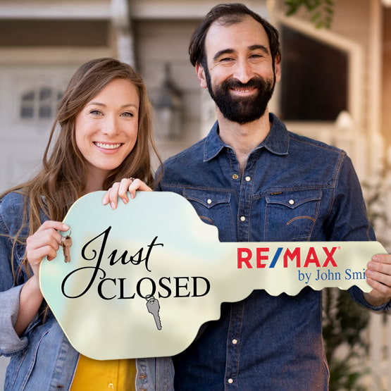 Happy Couple Outside Home Holding A House Key Shaped Ivory Acrylic Sign Printed With Just Closed Message And Logo And Name