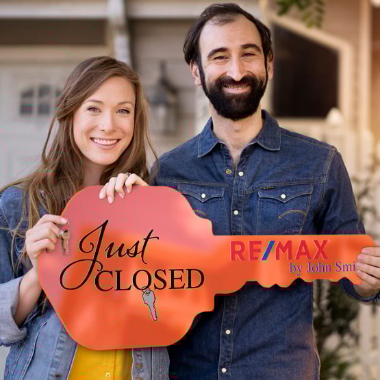 Happy Couple Outside Home Holding A House Key Shaped Orange Acrylic Sign Printed With Just Closed Message And Logo And Name