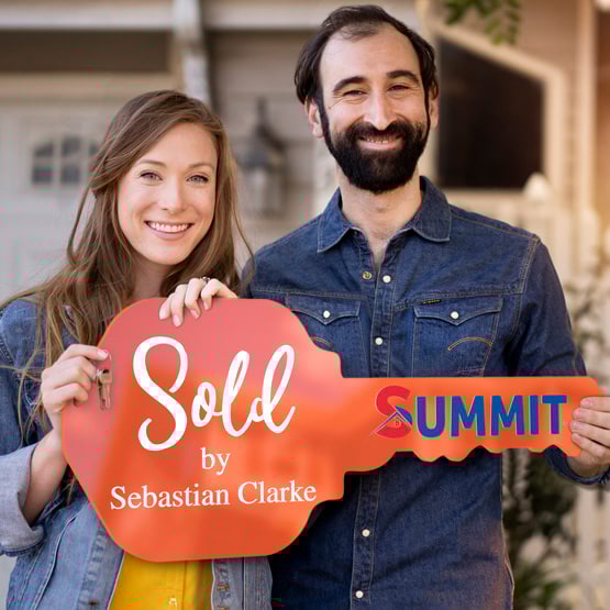 Happy Couple Outside Home Holding A House Key Shaped Orange Acrylic Sign Printed With Sold By Message And Logo And Name