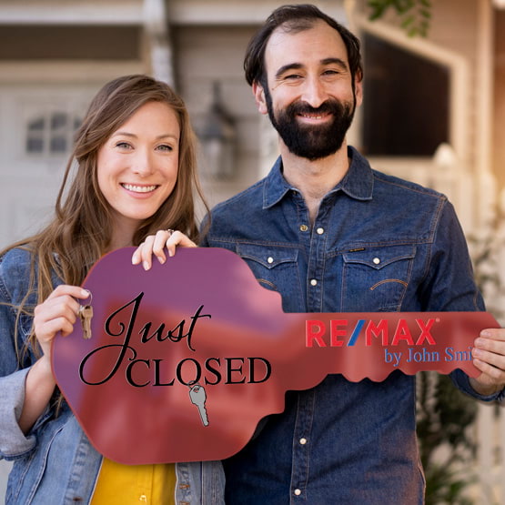 Happy Couple Outside Home Holding A House Key Shaped Red Acrylic Sign Printed With Just Closed Message And Logo And Name