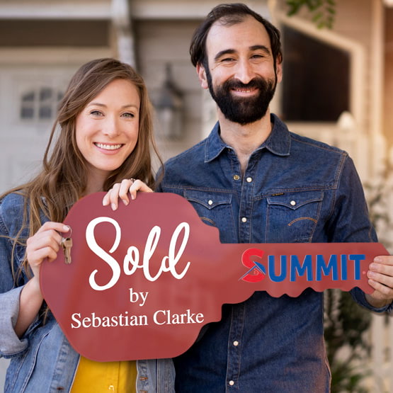 Happy Couple Outside Home Holding A House Key Shaped Red Acrylic Sign Printed With Sold By Message And Logo And Name